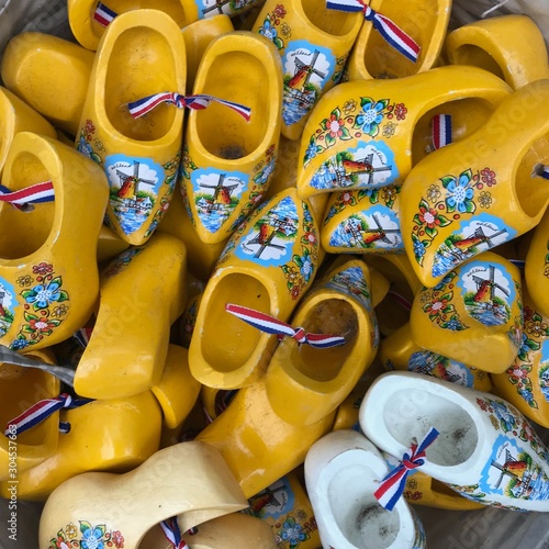 Large group of Tourist gifts shaped like little clogs with windmills and flowers in a basket in yellow and white photo