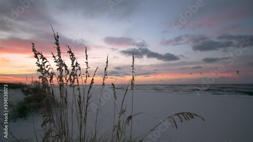 Subtle moody light at sunrise beach with pastel sky and clouds as the white sandy beach sits still.