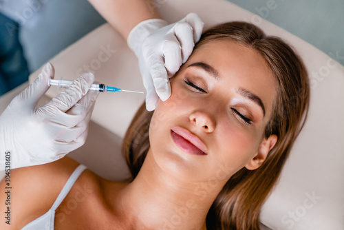 Young woman gets beauty facial injections in salon