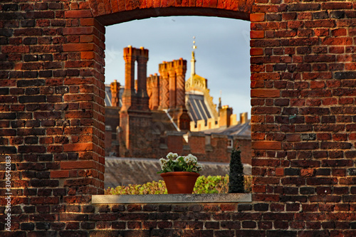 Fototapeta Hampton Court Palace with its famous Tudor chimneys seen through a window in a r