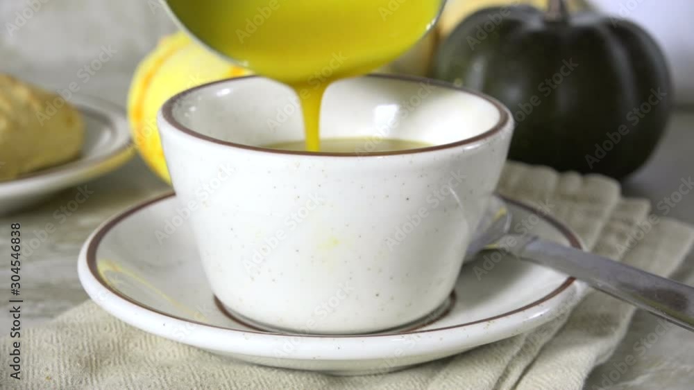 Serving a cup of homemade butternut squash soup with a ladle Serving a cup of homemade butternut squash soup with a ladle
