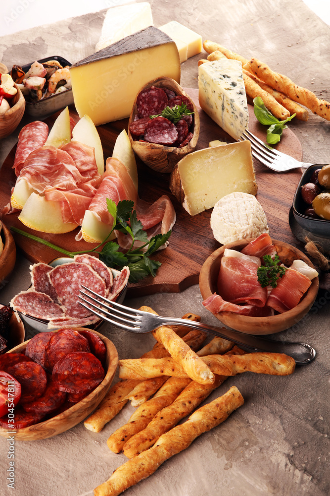 Italian antipasti wine snacks set. Cheese variety, Mediterranean olives, seafood salad, Prosciutto di Parma, tomatoes, anchovy and wine in glasses Italian antipasti wine snacks set. Cheese variety, Mediterranean olives, seafood salad, Prosciutto di Parma, tomatoes, anchovy and wine in glasses