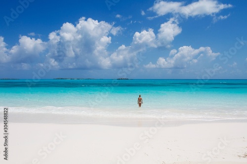 Beautiful girl entering into the turquoise sea of Exuma island  Bahamas 