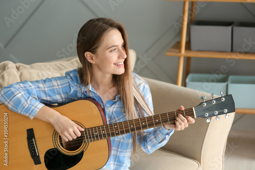 Young woman playing guitar ...
