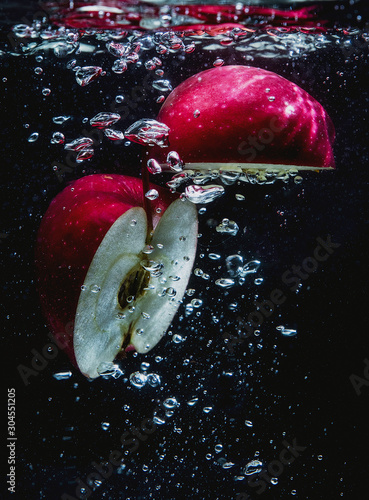 Red Apple cut in half in a splash of water, fresh, delicious Apple with splashes of water and air bubbles