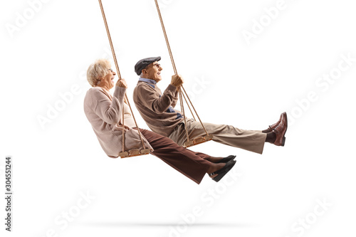 Elderly man and woman swinging on a wooden swings photo