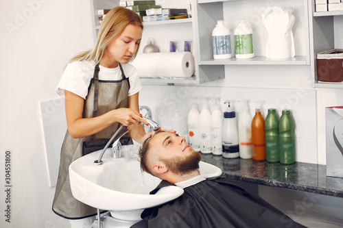 Man with a beard. Hairdresser with a client. Woman washing man's head