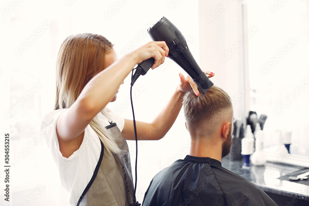 Man with a beard. Hairdresser with a client. Woman drying man's hair Man with a beard. Hairdresser with a client. Woman drying man's hair