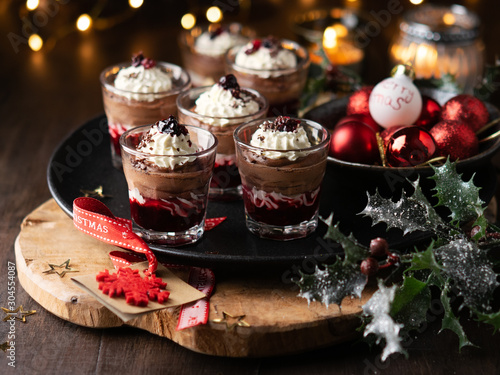 Canvastavla Dessert in a glasses with chocolate and berries spread on wooden background with garland lights bokeh and christmas decoration