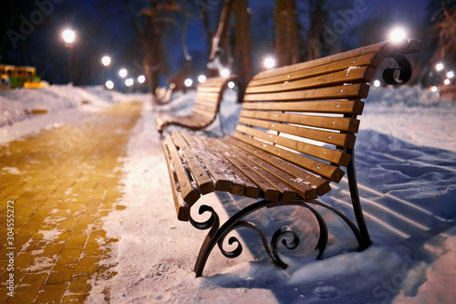 Fotografering Winter park with benches covered with snow in the evening.