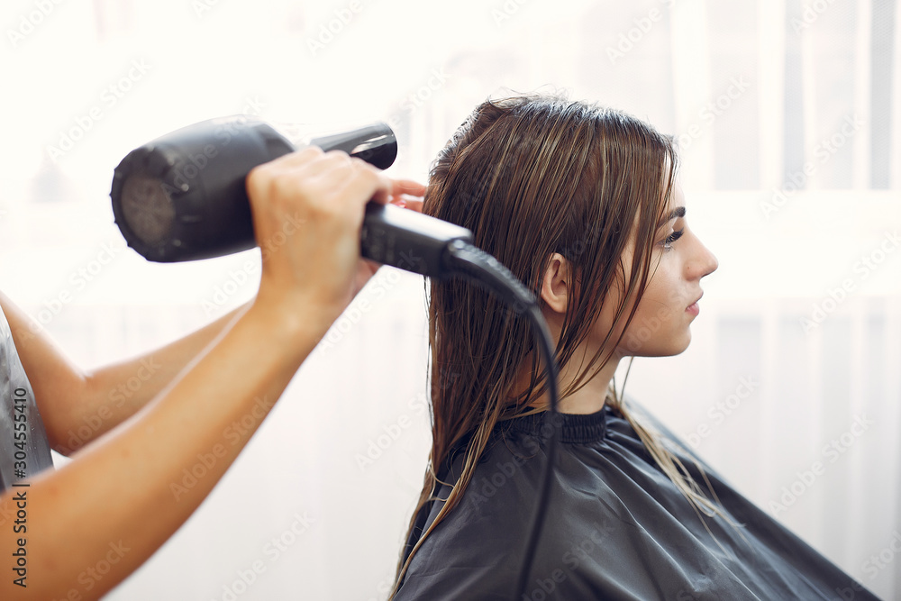 Fototapeta premium Hairdresser drying head her client. Woman in a hair salon