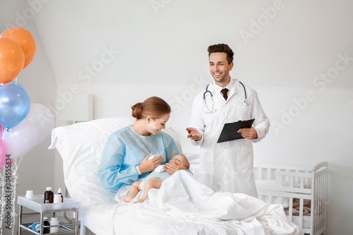 Young woman with newborn baby and gynecologist in maternity hospital