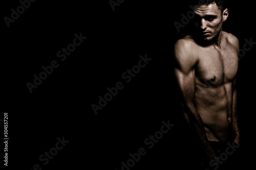 Fotografía Shirtless athletic masculine man over dark black background