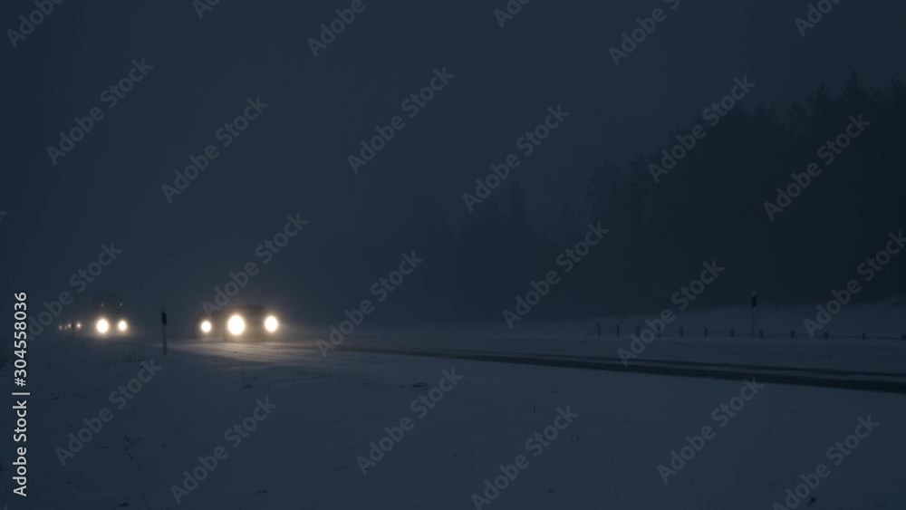 Snowstorm at night cars driving on icy and snowy highway Snowstorm at night cars driving on icy and snowy highway