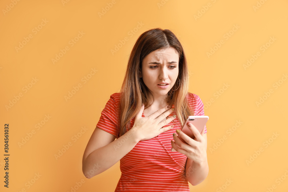 Portrait of worried young woman with mobile phone on color background Portrait of worried young woman with mobile phone on color background