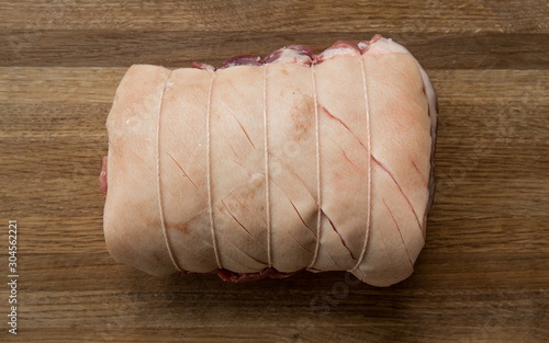 A raw Pork Shoulder cut of meat tied and scored for crackling with copy space