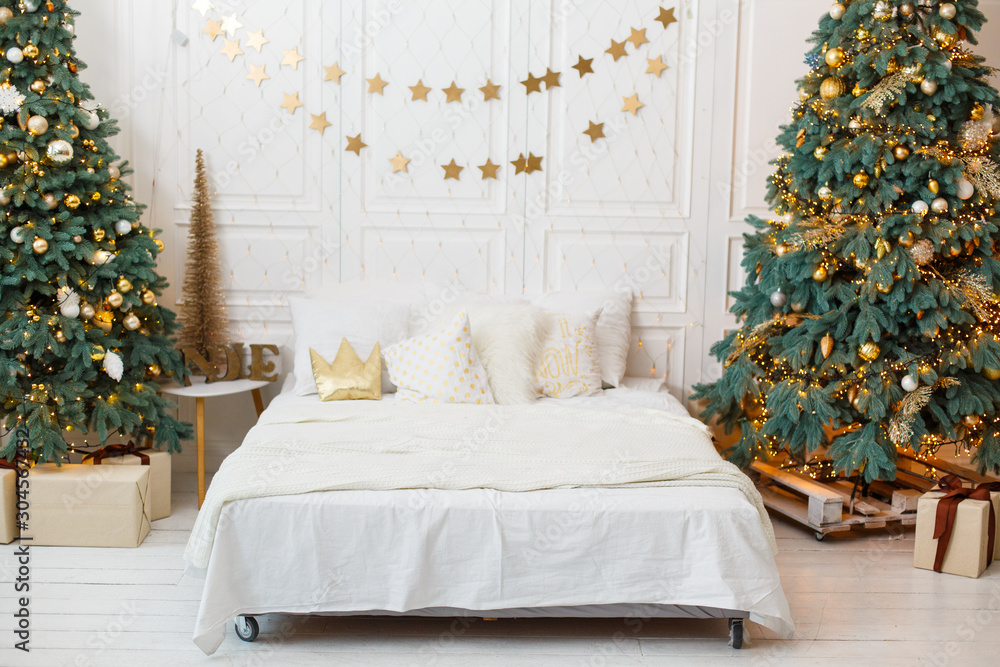 Romantic bedroom in light colors with a lot of garland lights decorated for New Year Celebrating. Christmas mood at home. White bedroom and Christmas spruces. Romantic interior. Breakfast in a bed - obrazy, fototapety, plakaty 