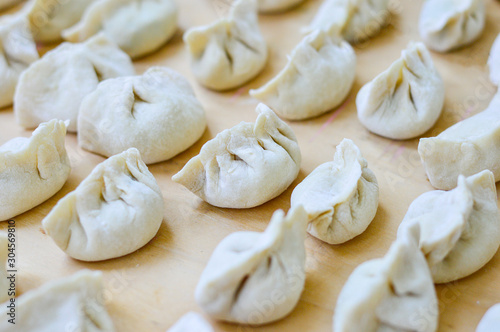 Close-up of Chinese Uncooked Dumplings Placed on Wooden Board.  The Dumplings, called Jiaozi in Chinese, is a popular traditional Chinese food, especially during Chinese New Year. © MJ