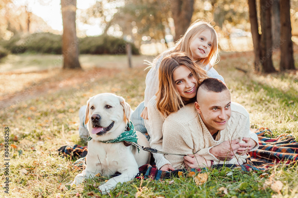 Happy family is having fun with dog labrador are lying on green grass in park. Happy family is having fun with dog labrador are lying on green grass in park.