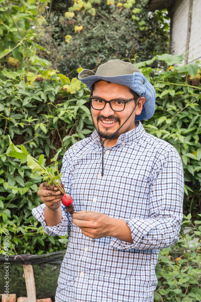 Young latin man with hat a blue shirt holding a radish