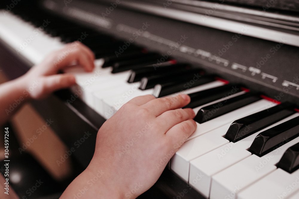 hands on white and black keys of a synthesizer close-up with musical inscriptions hands on white and black keys of a synthesizer close-up with musical inscriptions