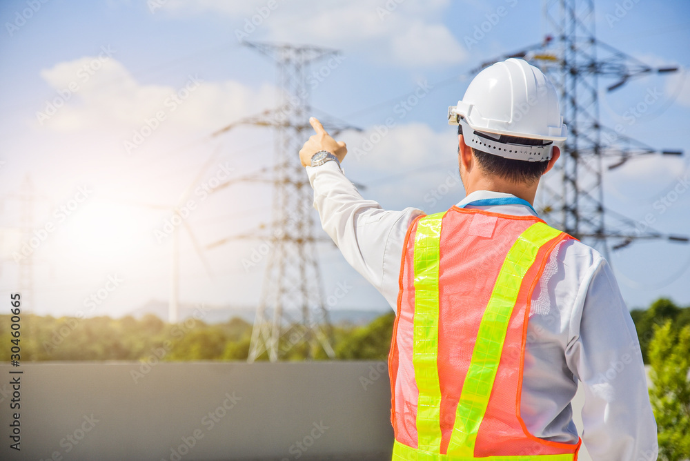 Electrical engineer standing holding his hand up Sky high voltage pole background Electrical engineer standing holding his hand up Sky high voltage pole background