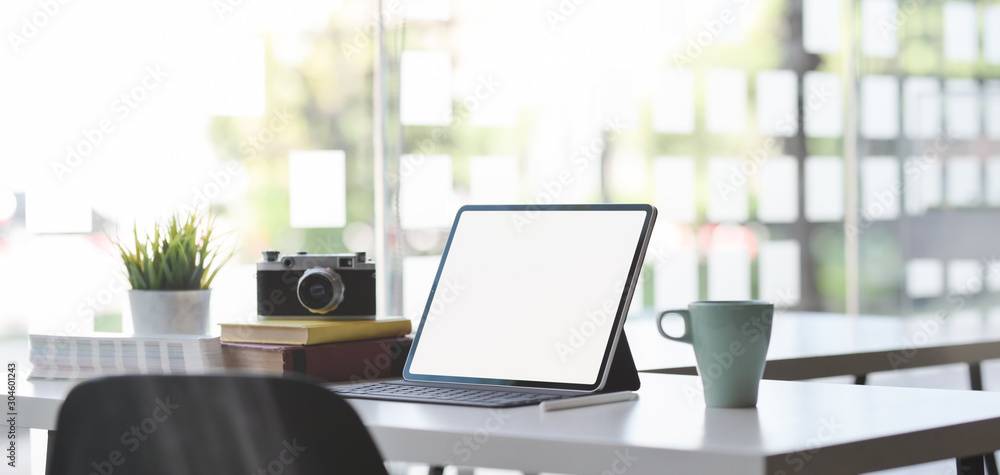 Comfortable office room with mock up digital tablet, camera and office supplies with sunlight in the background Comfortable office room with mock up digital tablet, camera and office supplies with sunlight in the background