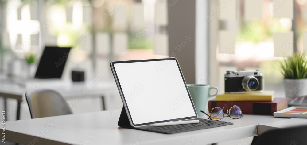 Close-up view of comfortable designer workplace with blank screen digital tablet, camera and office supplies Close-up view of comfortable designer workplace with blank screen digital tablet, camera and office supplies