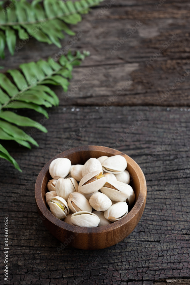 Pistachio nut in wooden bowl on rusty wood table background Pistachio nut in wooden bowl on rusty wood table background