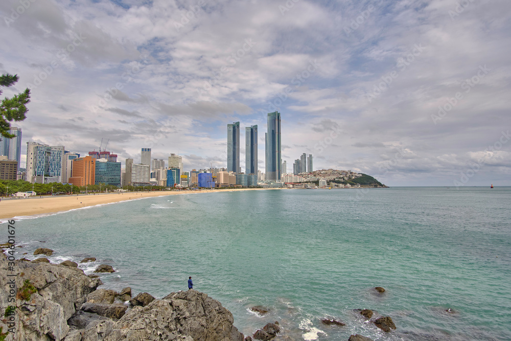 Naklejka premium Scenic view of awesome rocky beach, sea and skyscrapers in Busan in South Korea. Beautiful summer cloudy look of relax place in resort city of Republic of Korea