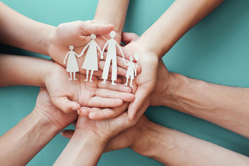 hands holding paper family cutout, family home,adoption foster care, homeless charity, family mental health,  homeschooling , household budget during recession concept