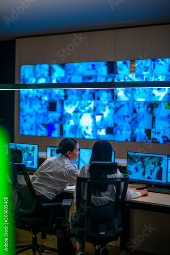 Female security guards working in surveillance room, monitoring cctv and discussing. photo