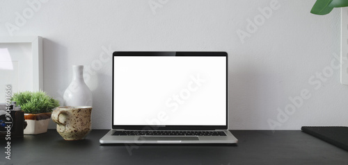 Cropped shot of open blank screen laptop computer with office supplies and copy space in modern office