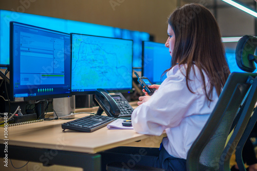 Fotografia Female security guard sitting and monitoring modern CCTV cameras in a surveillance room