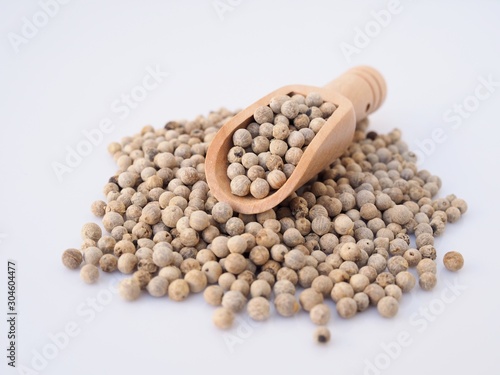 White pepper in wooden spoon isolated on white background
