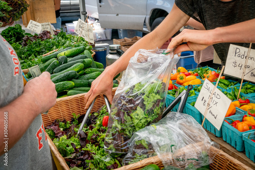 Woman bagging fresh greens at a local farmer's market in Southern Oregon