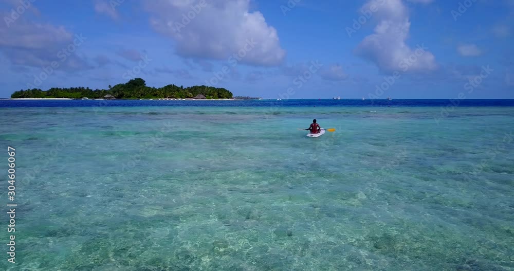 Guy with canoe paddling across crystal water of shallow lagoon, toward deep blue sea, far from tropical island's shore in Seychelles Guy with canoe paddling across crystal water of shallow lagoon, toward deep blue sea, far from tropical island's shore in Seychelles