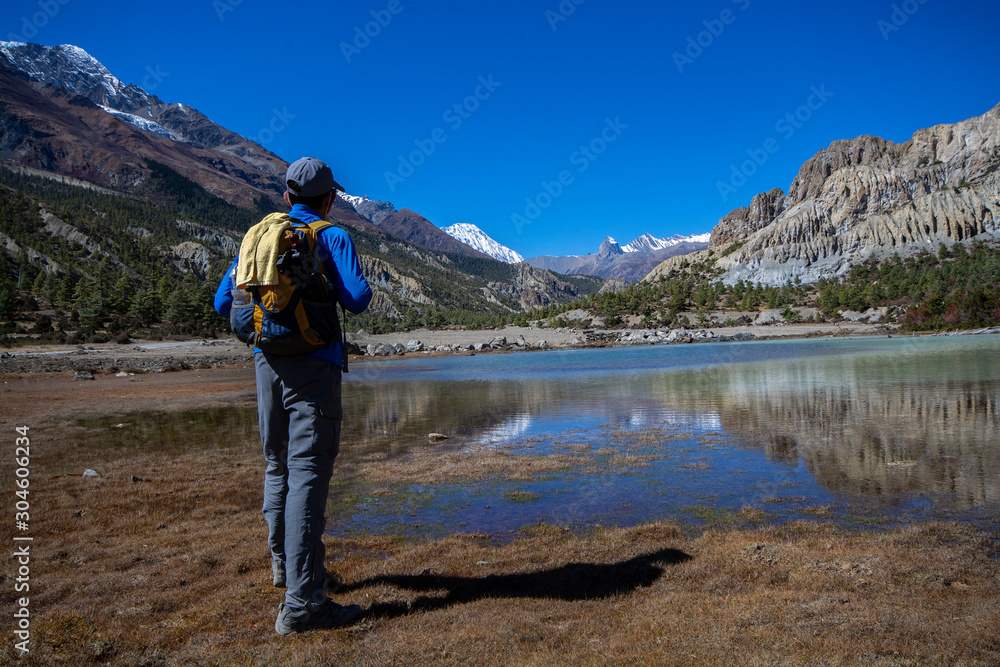 Man standing to look at view of lake with snow mountains background