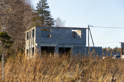 Two-storey house under construction from a foam block in a cottage village. Autumn, sunny