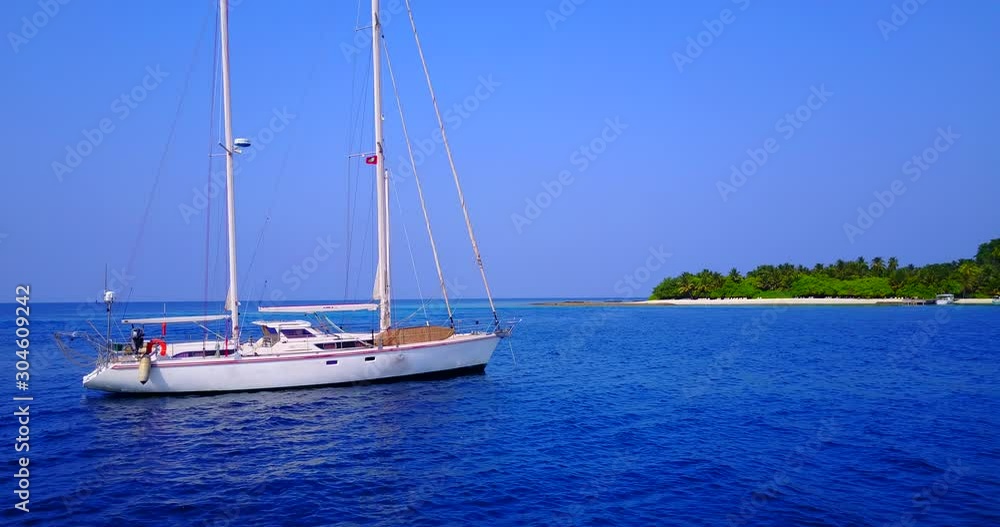 Bahamas, North America - A Yacht Traveling Through The Deep Blue Ocean With Nearby Lush Green Island Under The Bright Blue Sky - Wide Shot Bahamas, North America - A Yacht Traveling Through The Deep Blue Ocean With Nearby Lush Green Island Under The Bright Blue Sky - Wide Shot