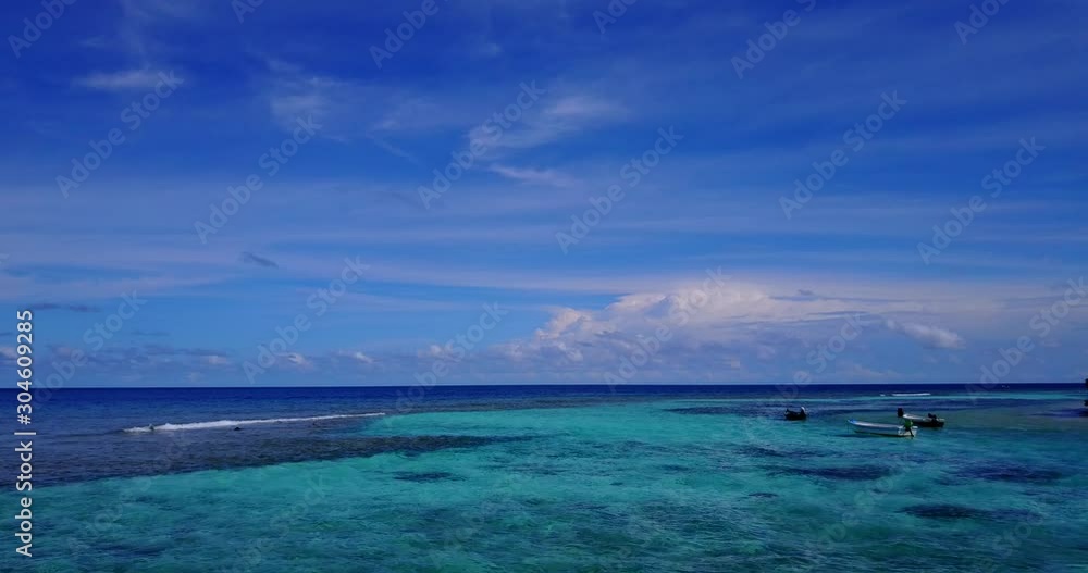 Boats floating on a calm area of turquoise lagoon with clear calm water divided by coral reef barrier from deep blue vibrant sea under a beautiful cloudy sky Boats floating on a calm area of turquoise lagoon with clear calm water divided by coral reef barrier from deep blue vibrant sea under a beautiful cloudy sky