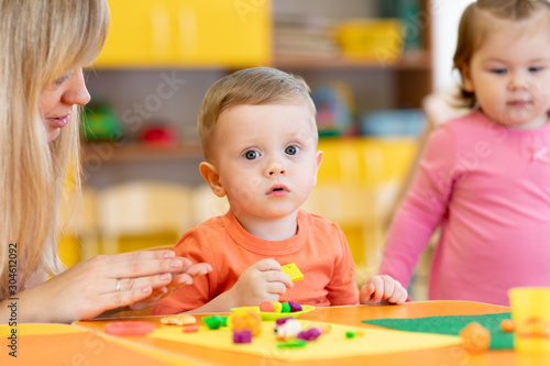 Children with teacher play plasticine in kindergarten