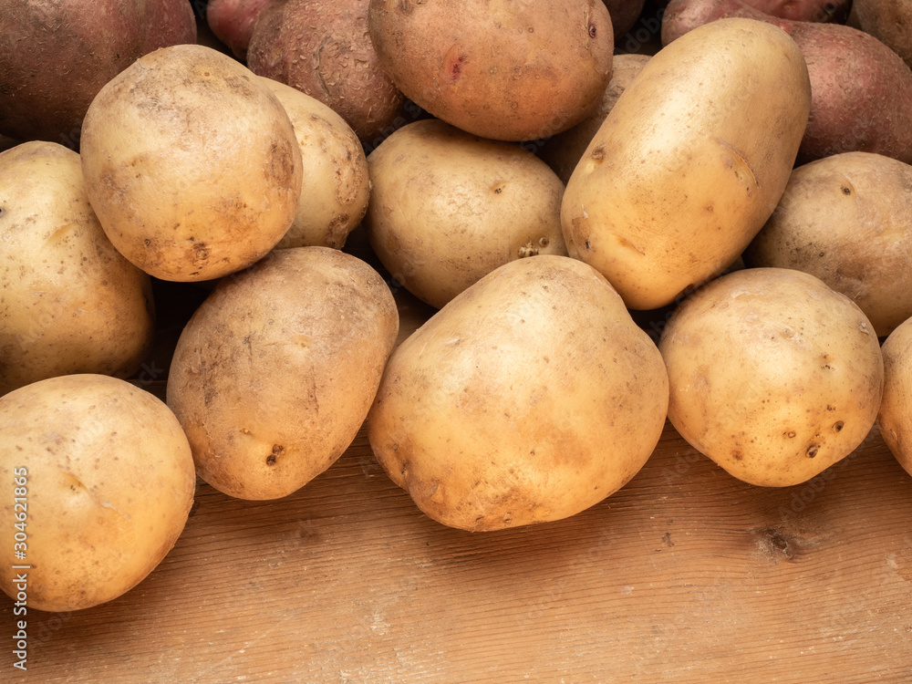 Rustic potatoes. Vegetables from farmhouse field is lying in bulk on wooden table from planks Rustic potatoes. Vegetables from farmhouse field is lying in bulk on wooden table from planks