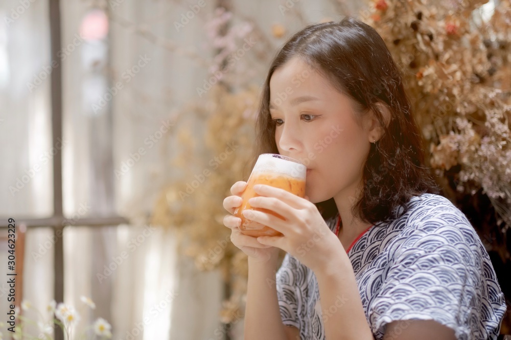 Asian girl drinking a glass of milk tea in cafe Asian girl drinking a glass of milk tea in cafe