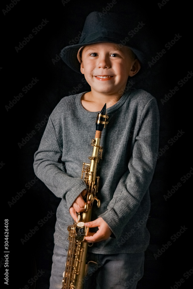 Naklejka premium happy child plays saxophone in studio