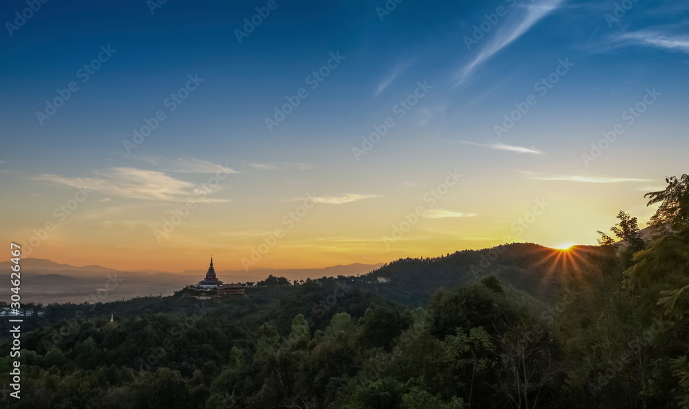 Mountain view panorama evening of Crystal Pagoda or Chedi Kaew on top hill with red sun light and blue sky background, sunset at Wat Tha Ton, Tha Ton District, Fang, Chiang Mai, northern of Thailand.