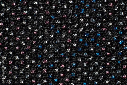 the texture of the dark fabric (for clothing) with rhinestones, beads. Close-up (macro). Background