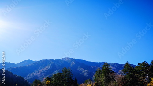 Scenic landscape view of nature forest with mountain range hills trees and clear blue sky background in fall autumn season of kamikochi, in Hotaka Ranges, Kamikochi, Japan.