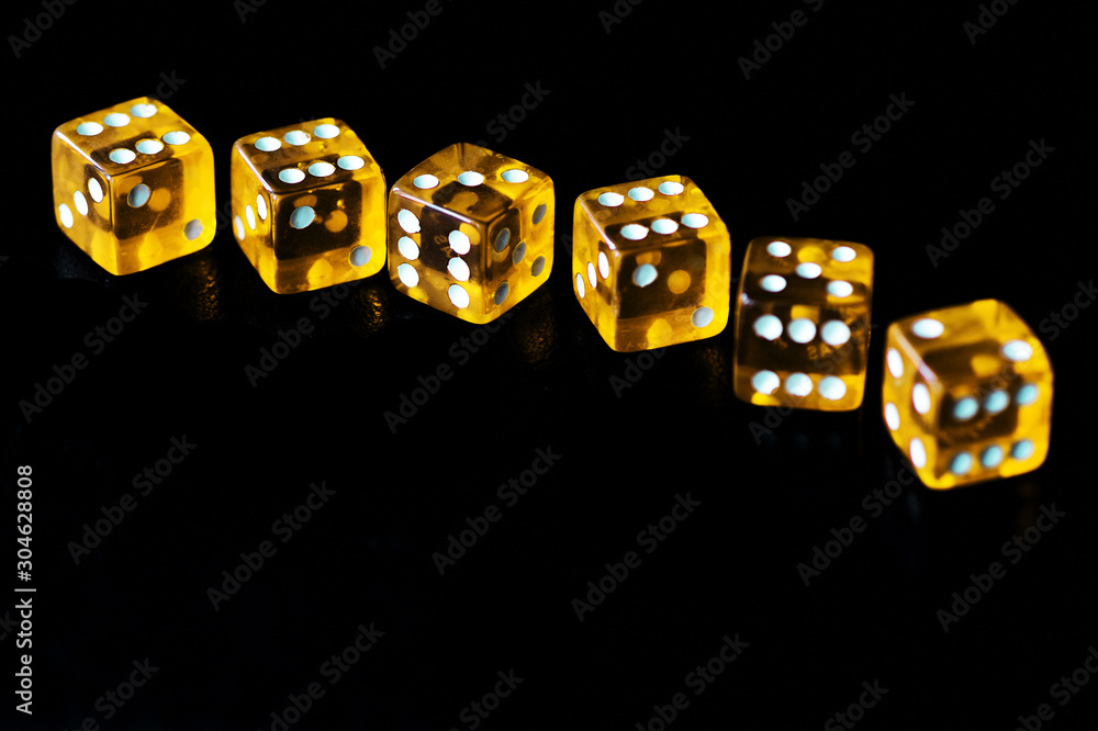 Several transparent yellow dice on a black surface close-up. Gambling сoncept background Several transparent yellow dice on a black surface close-up. Gambling сoncept background