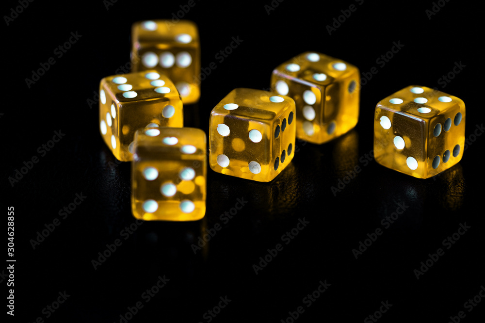 Several transparent yellow dice on a black surface close-up. Gambling сoncept background Several transparent yellow dice on a black surface close-up. Gambling сoncept background